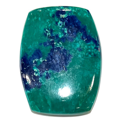 A polished, cushion shaped chrysocolla stone with azurite inclusions.