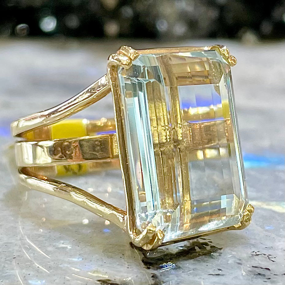 Large ladies' emerald cut aquamarine solitaire cocktail ring in yellow gold.