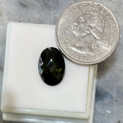 A loose faceted oval checkerboard cut moldavite stone.