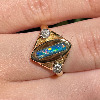 Lightning Ridge black opal set between two round diamonds in an 18 karat yellow gold ring.  Anaheim, California.