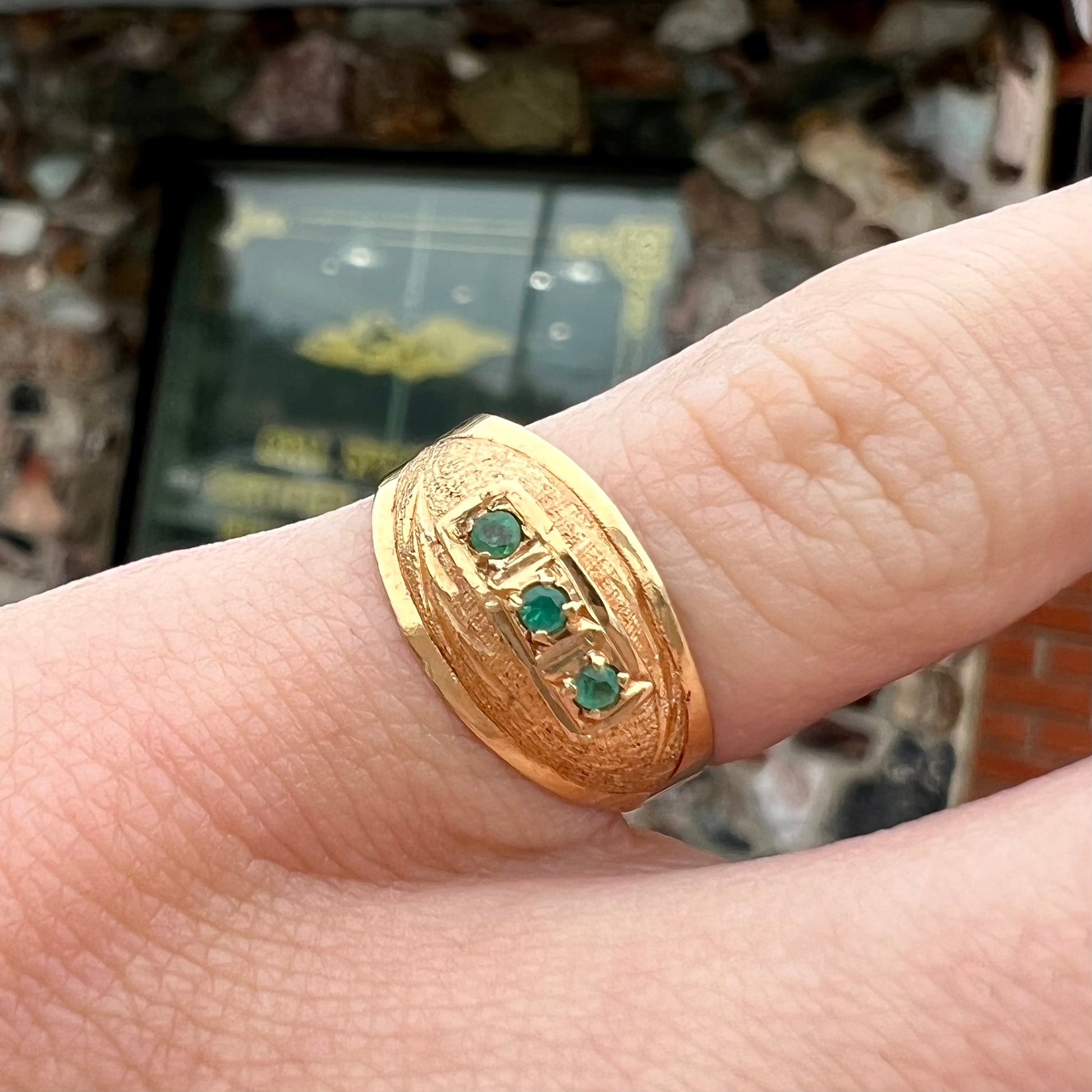 A 1920's style yellow gold three stone round cut emerald ring.