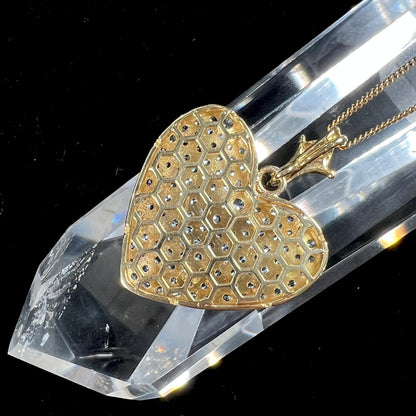 A gold heart pendant pave set with round aquamarine stones.