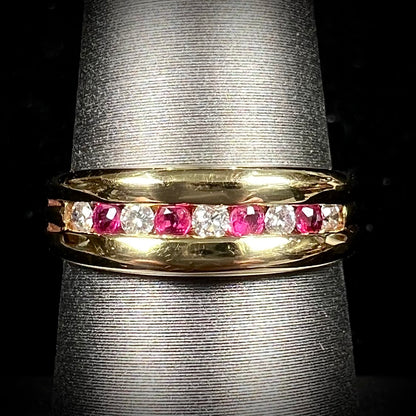 An 18kt yellow gold band channel set with round cut rubies and diamonds.