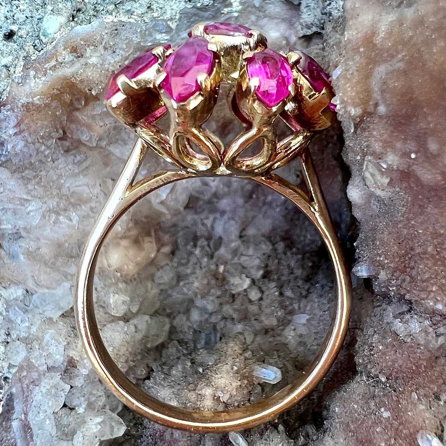 A yellow gold pink Burma ruby cluster ring with a faceted oval center stone surrounded by marquise cut stones.