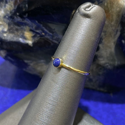 Round cabochon cut blue lapis lazuli stone set in a dainty simple yellow gold solitaire ring.