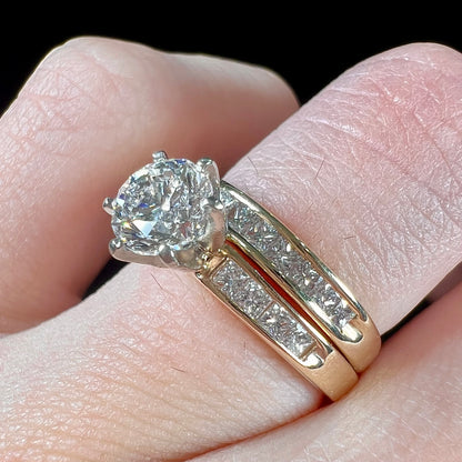 A diamond engagement and wedding ring set.  The center stone is a 1 carat round diamond, and the side stones are channel set princess cut diamonds.