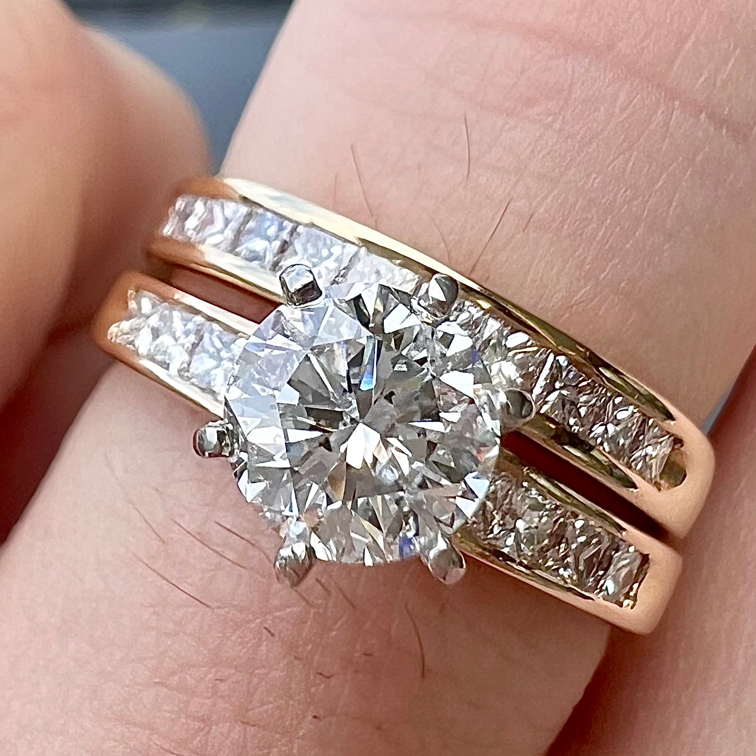 A diamond engagement and wedding ring set.  The center stone is a 1 carat round diamond, and the side stones are channel set princess cut diamonds.