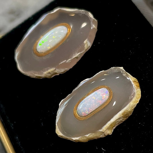 Earrings featuring oval cut white crystal opal cabochons set in slices of polished agate with yellow gold bezels.