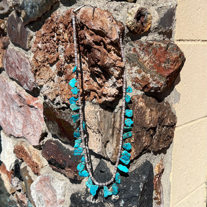 A Santo Domingo puka shell bead necklace with drilled turquoise nuggets attached.