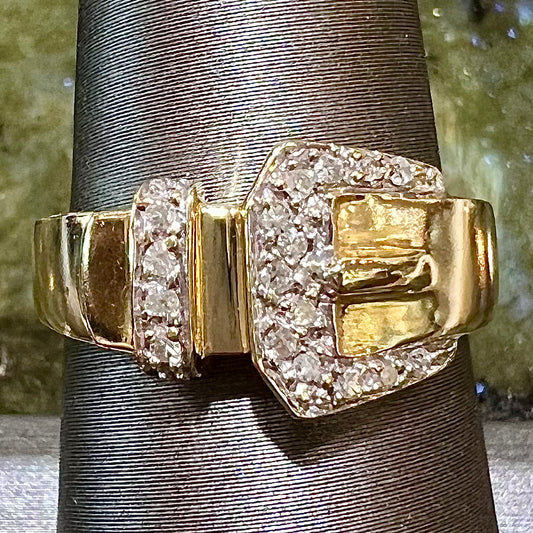 A yellow gold buckle ring set with round diamonds in the buckle.