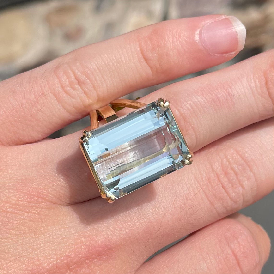 Large ladies' emerald cut aquamarine solitaire cocktail ring in yellow gold.
