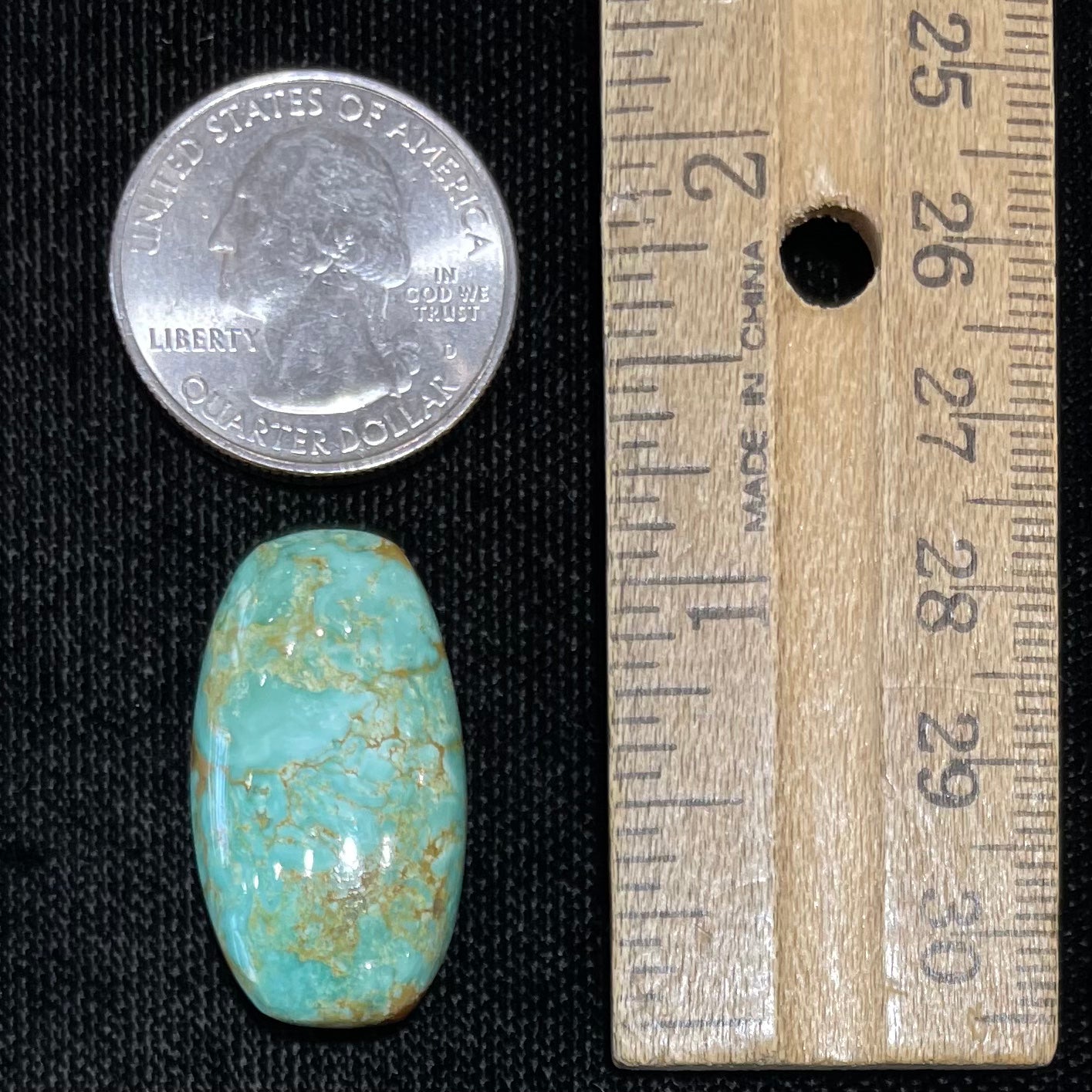 A loose, cabochon cut, green turquoise stone with brown matrix.