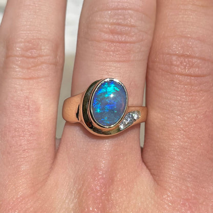 A yellow gold ring set with diamonds and a Lightning Ridge black opal from Australia.
