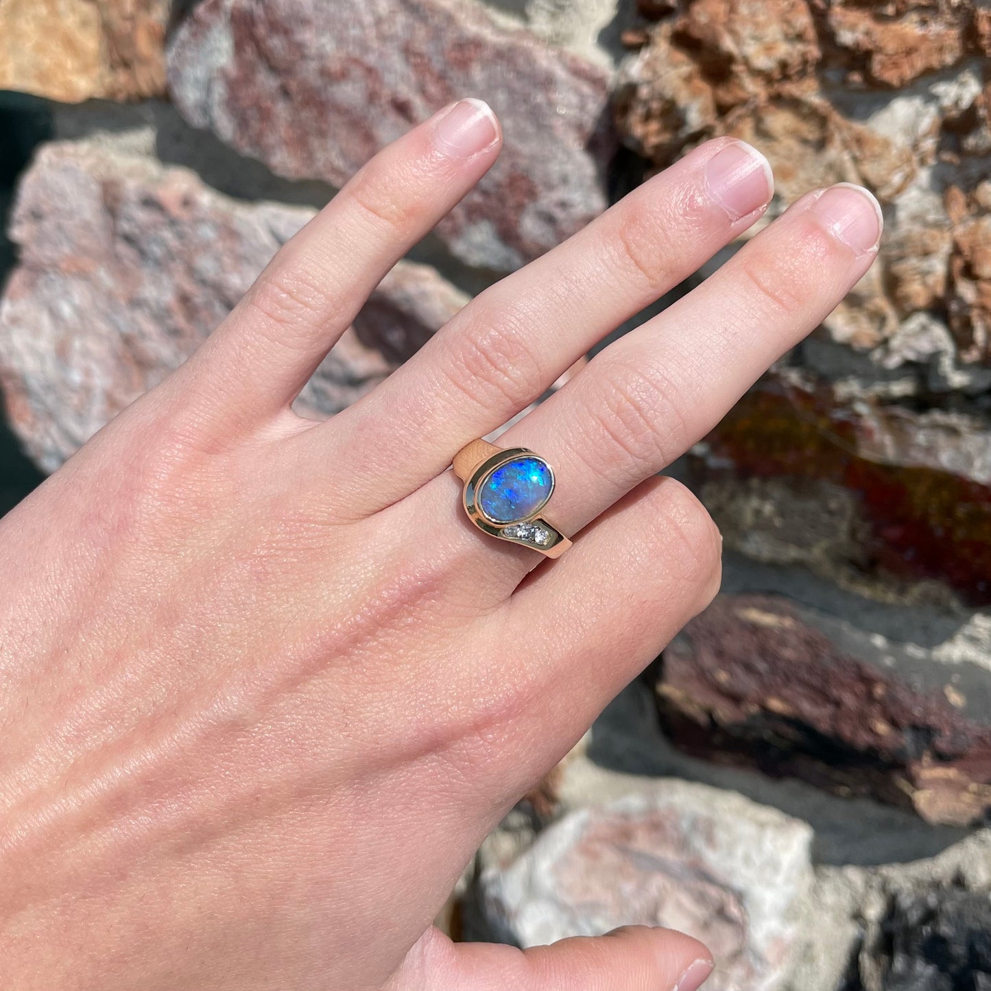 A yellow gold ring set with diamonds and a Lightning Ridge black opal from Australia.