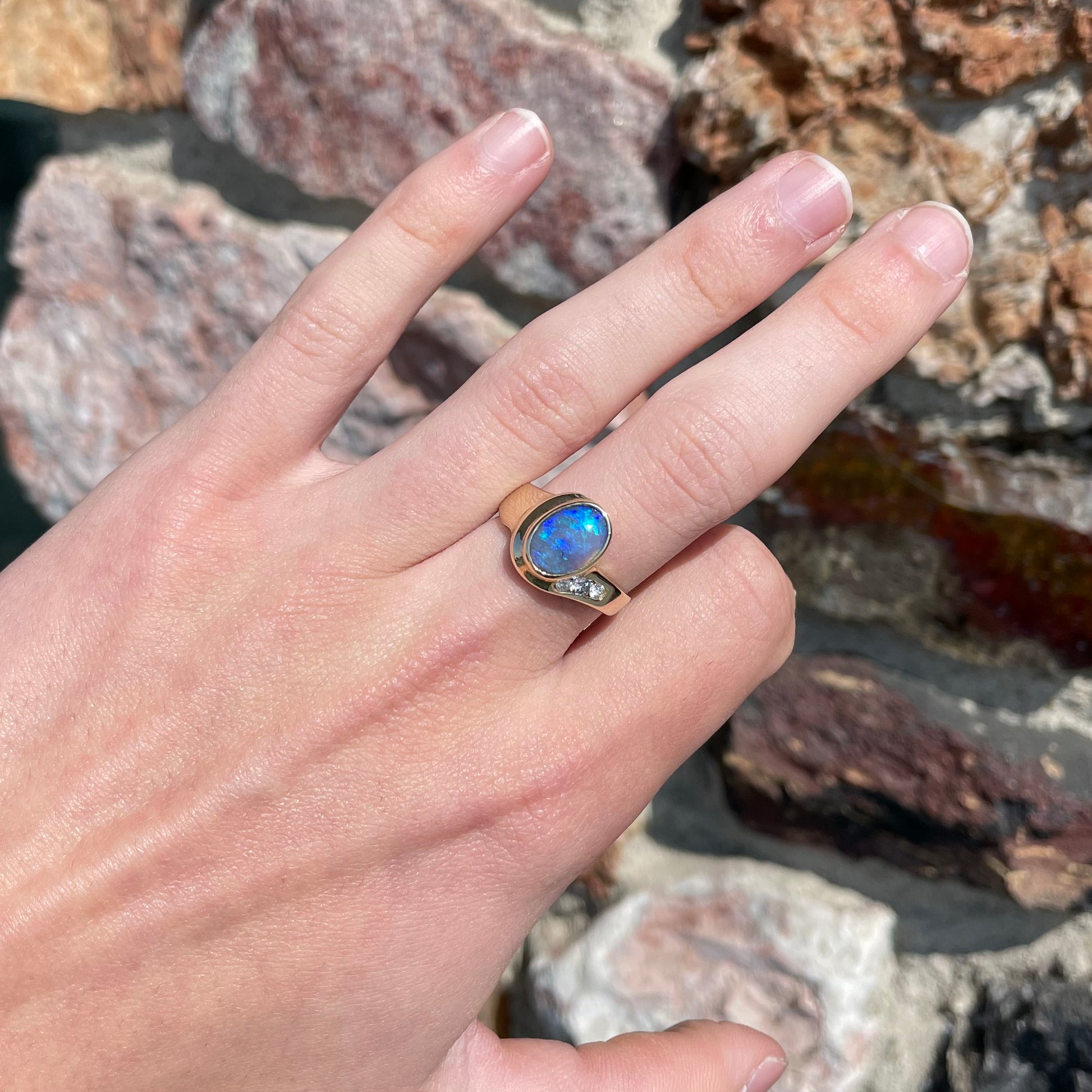 A yellow gold ring set with diamonds and a Lightning Ridge black opal from Australia.