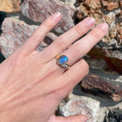 A yellow gold ring set with diamonds and a Lightning Ridge black opal from Australia.