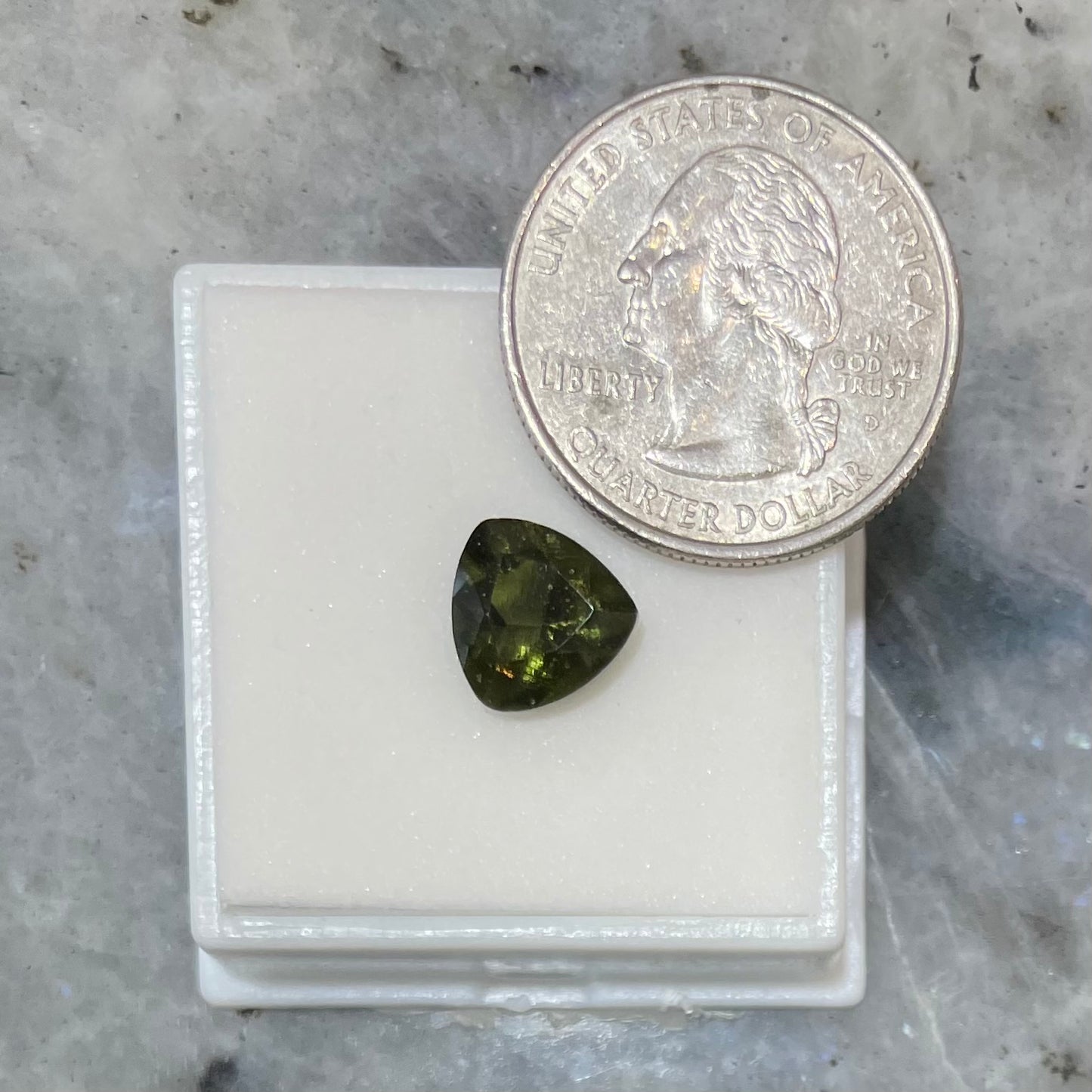 A loose, faceted trillion cut moldavite stone that weighs 2.73 carats.