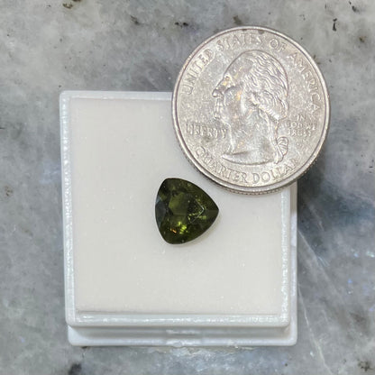 A loose, faceted trillion cut moldavite stone that weighs 2.73 carats.