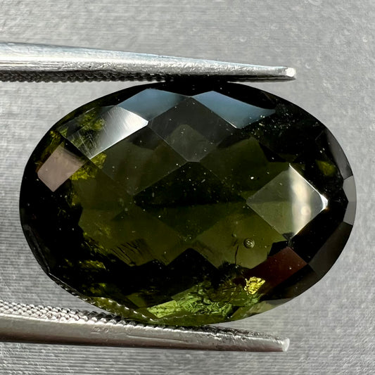 A loose faceted oval checkerboard cut moldavite stone.