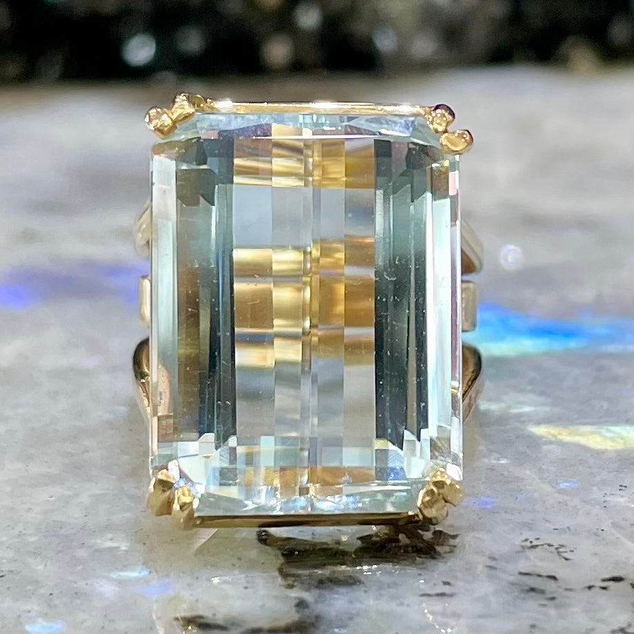Large ladies' emerald cut aquamarine solitaire cocktail ring in yellow gold.