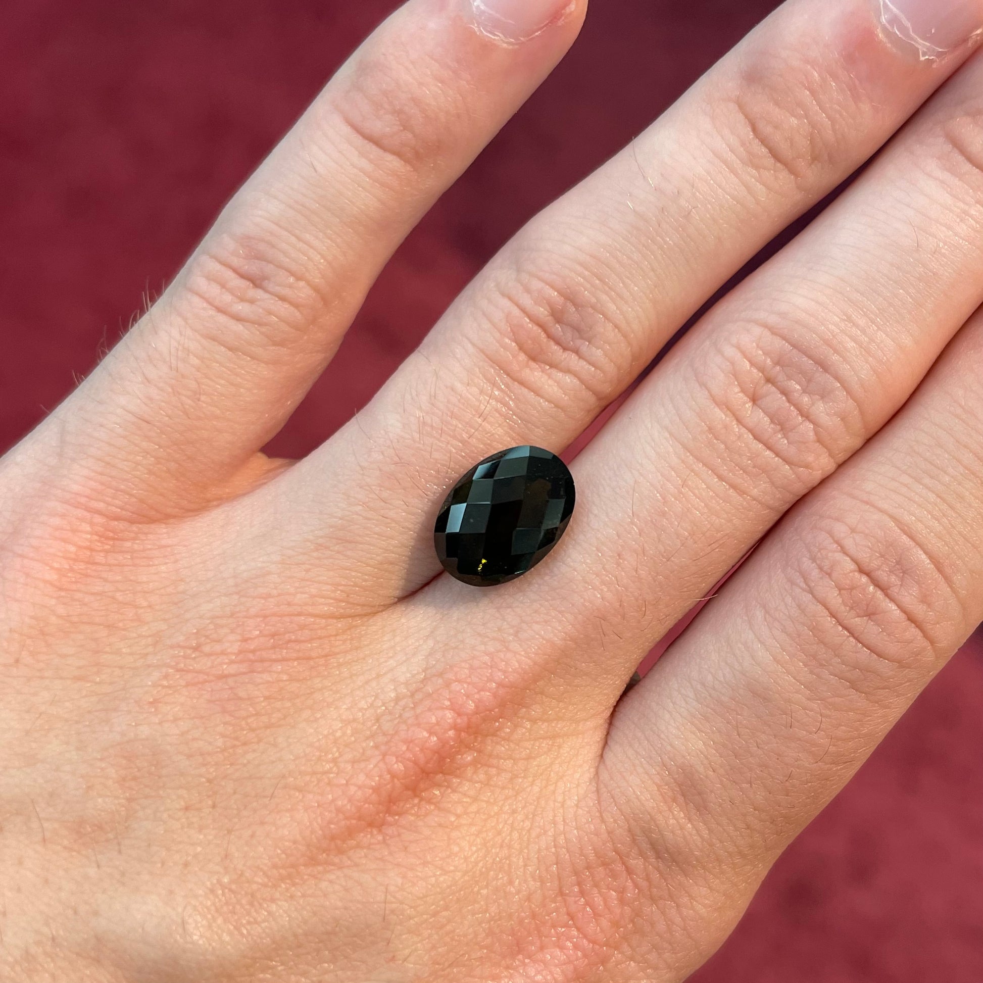A loose faceted oval checkerboard cut moldavite stone.