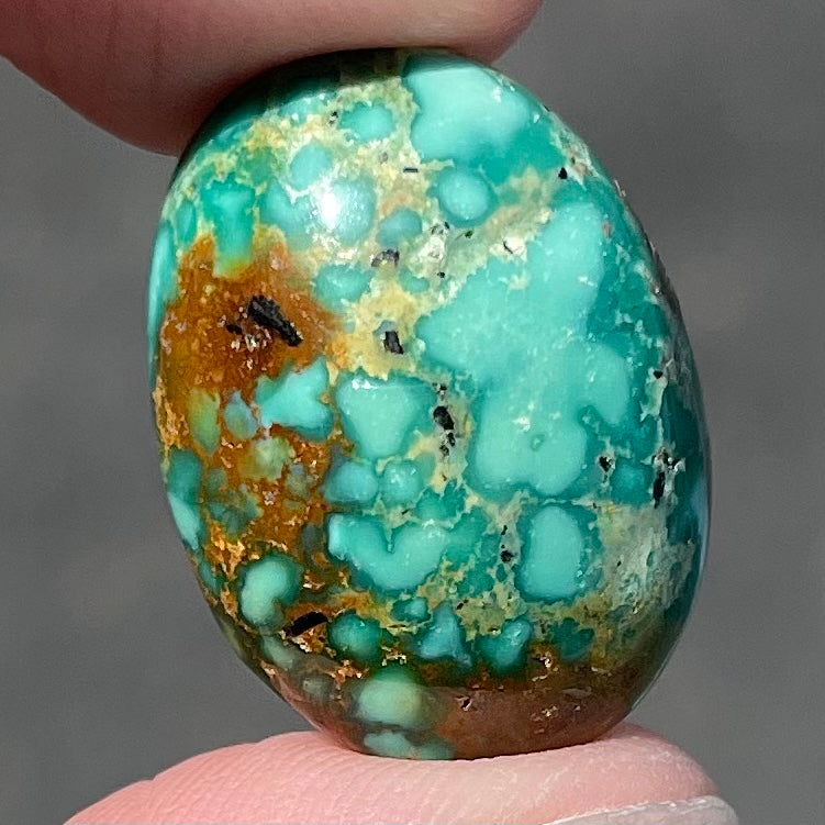 A loose, oval cabochon cut green and brown turquoise stone from Royston Mining District, Nevada.
