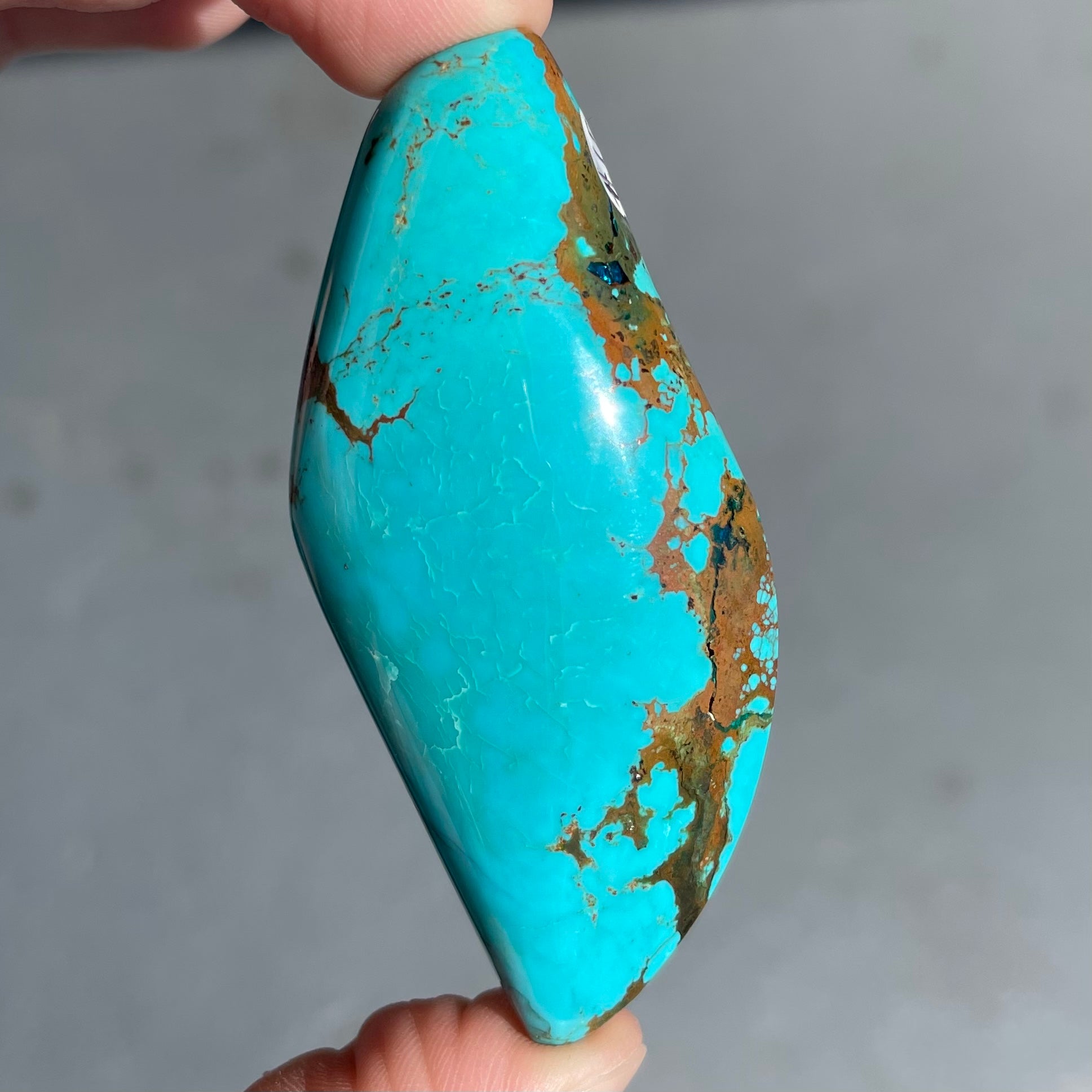 A freeform cabochon cut Bisbee turquoise stone.  The stone has been dyed to improve color.