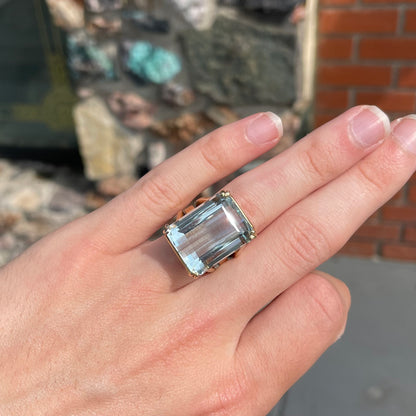 Large ladies' emerald cut aquamarine solitaire cocktail ring in yellow gold.