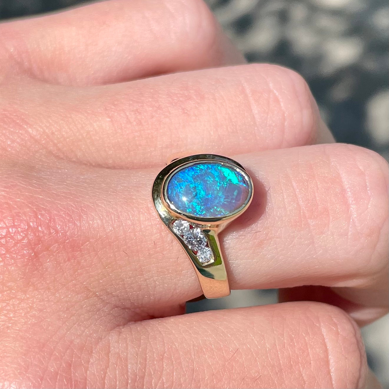A yellow gold ring set with diamonds and a Lightning Ridge black opal from Australia.