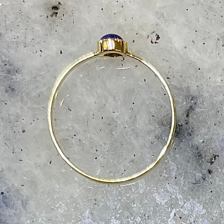 Round cabochon cut blue lapis lazuli stone set in a dainty simple yellow gold solitaire ring.