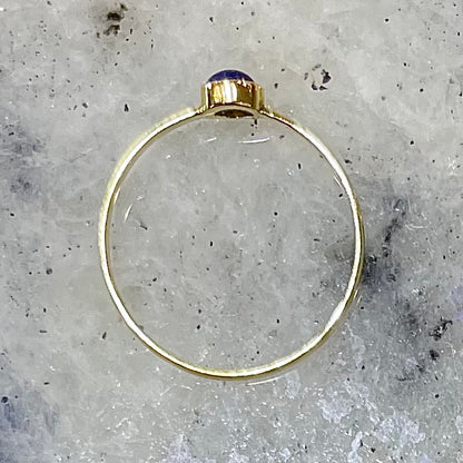 Round cabochon cut blue lapis lazuli stone set in a dainty simple yellow gold solitaire ring.