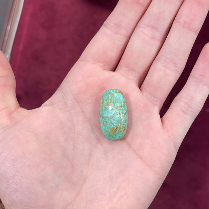A loose, cabochon cut, green turquoise stone with brown matrix.