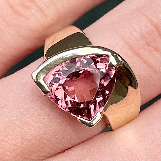 A unisex trillion cut pink tourmaline ring half bezel set in 14k yellow gold.