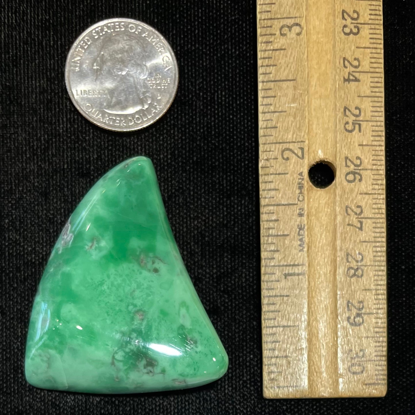 A loose, polished triangular cabochon cut variscite stone from Utah, USA.