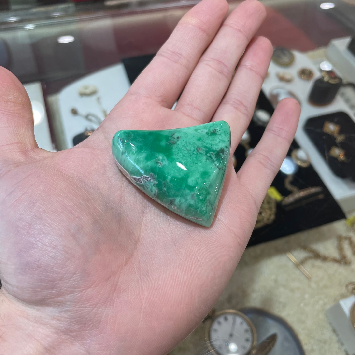 A loose, polished triangular cabochon cut variscite stone from Utah, USA.