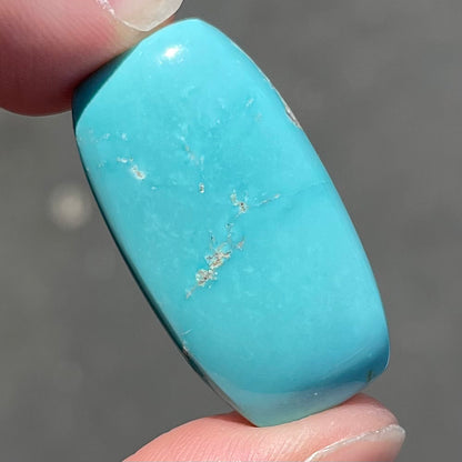 A loose, barrel cabochon cut sky blue turquoise stone from Sleeping Beauty Mine, Arizona.