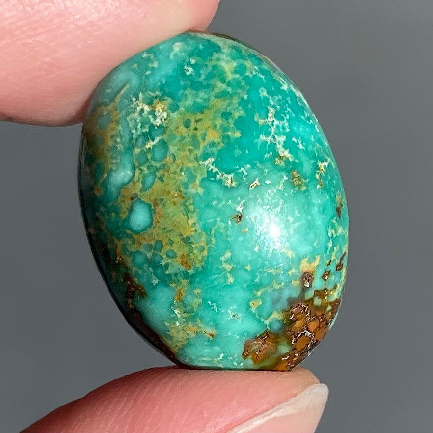 A loose, oval cabochon cut, green turquoise stone from Royston Mining District, Nevada.