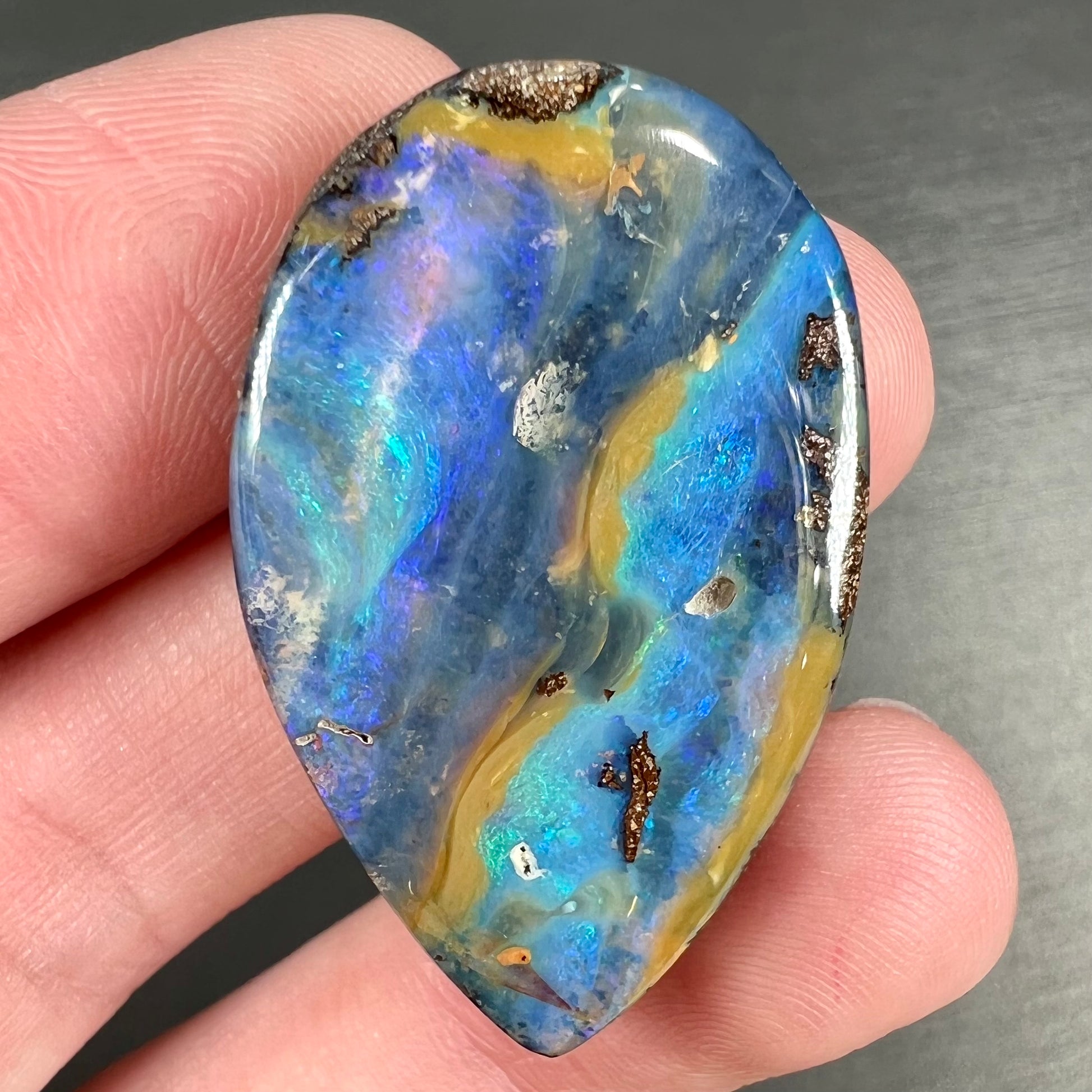 A loose, pear shaped cabochon cut boulder opal stone from Quilpie, Australia.