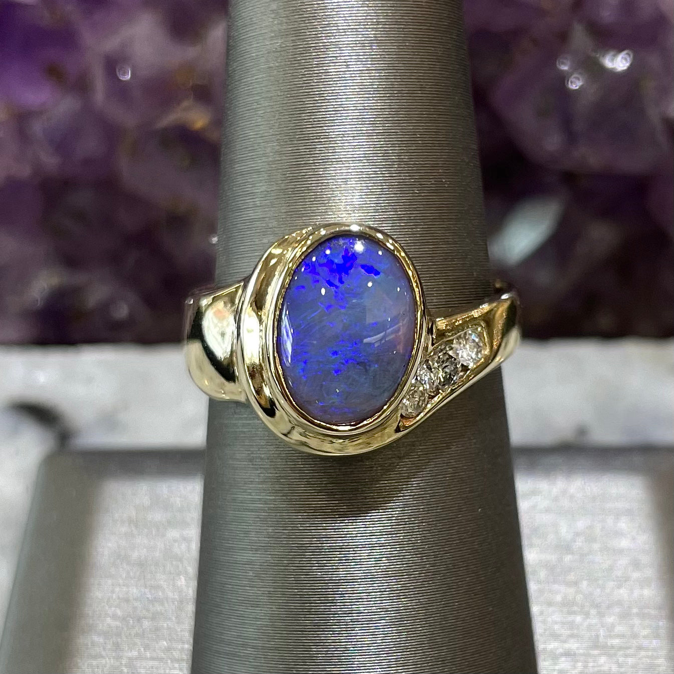 A yellow gold ring set with diamonds and a Lightning Ridge black opal from Australia.