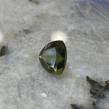 A loose, faceted trillion cut moldavite stone that weighs 2.73 carats.