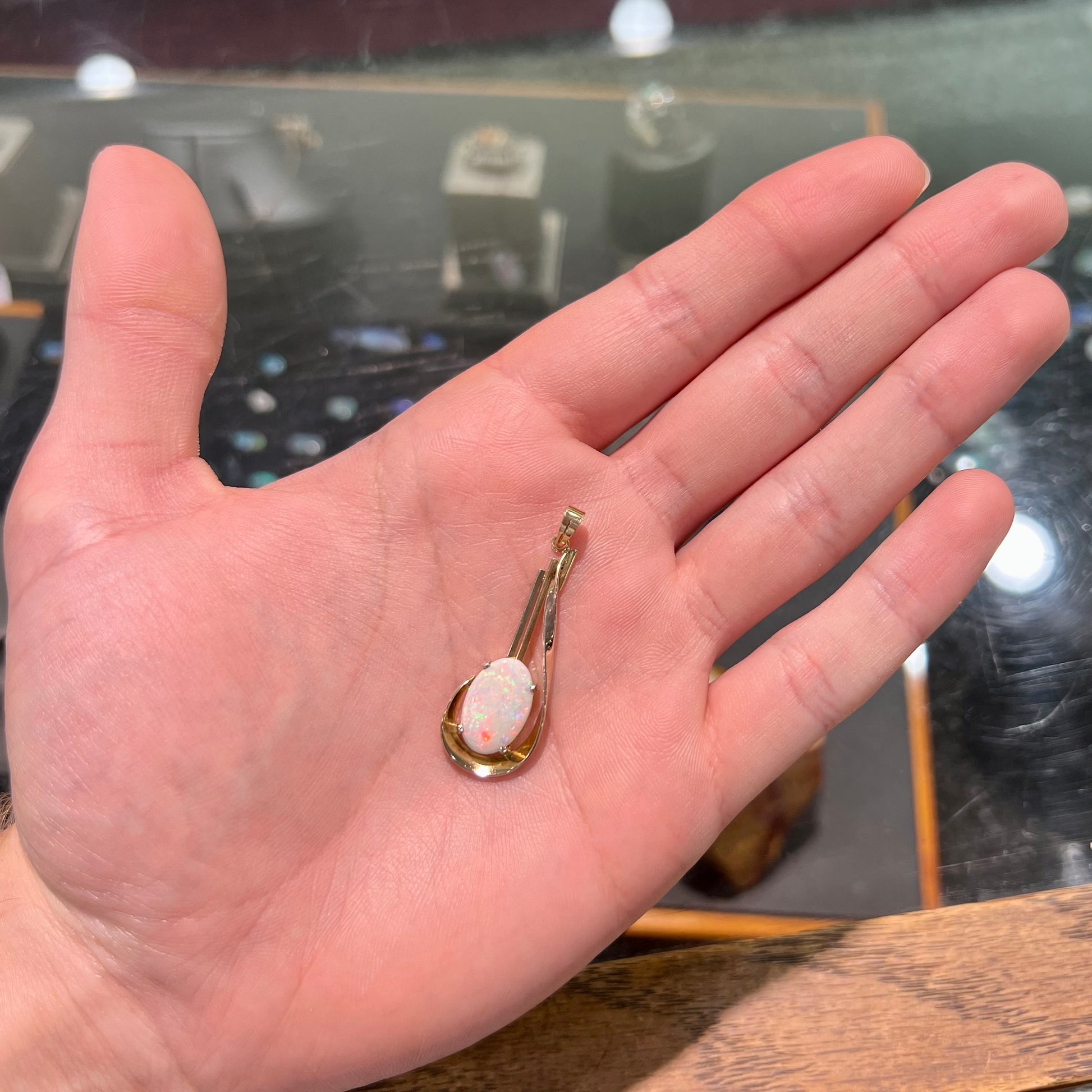 A handmade gold drop pendant set with an oval cabochon cut white crystal opal.