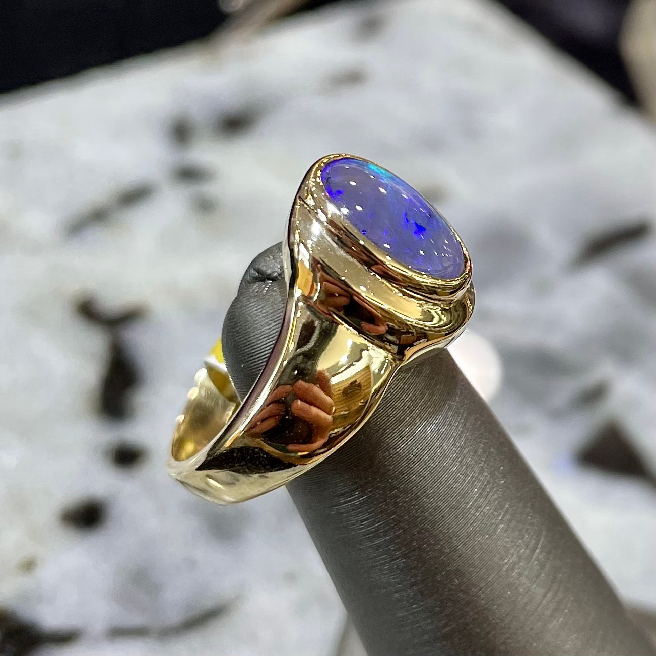 A yellow gold ring set with diamonds and a Lightning Ridge black opal from Australia.