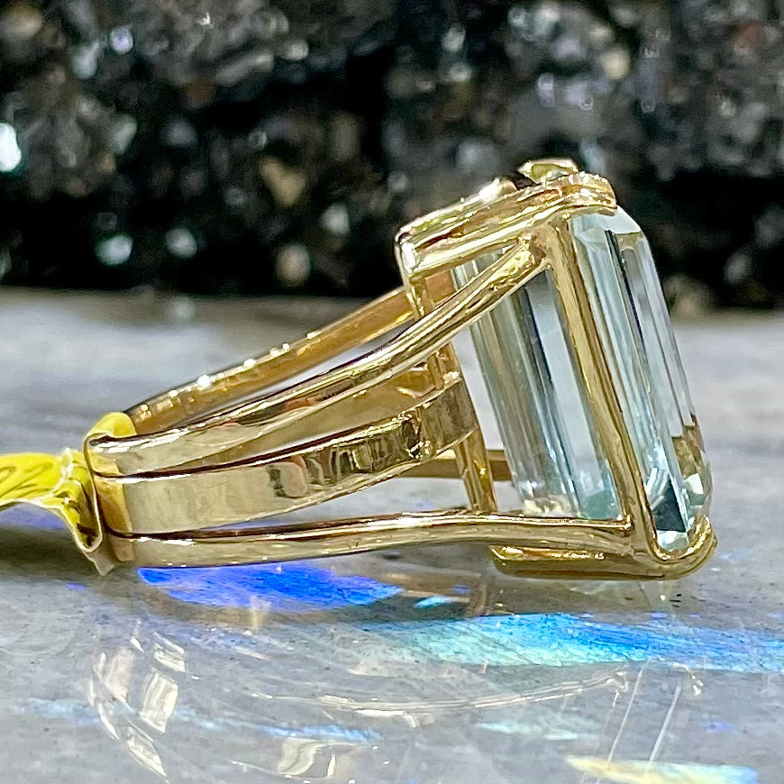 Large ladies' emerald cut aquamarine solitaire cocktail ring in yellow gold.