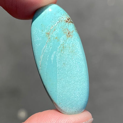 A loose, light blue, oval cabochon cut turquoise stone from Sleeping Beauty Mine, Arizona.