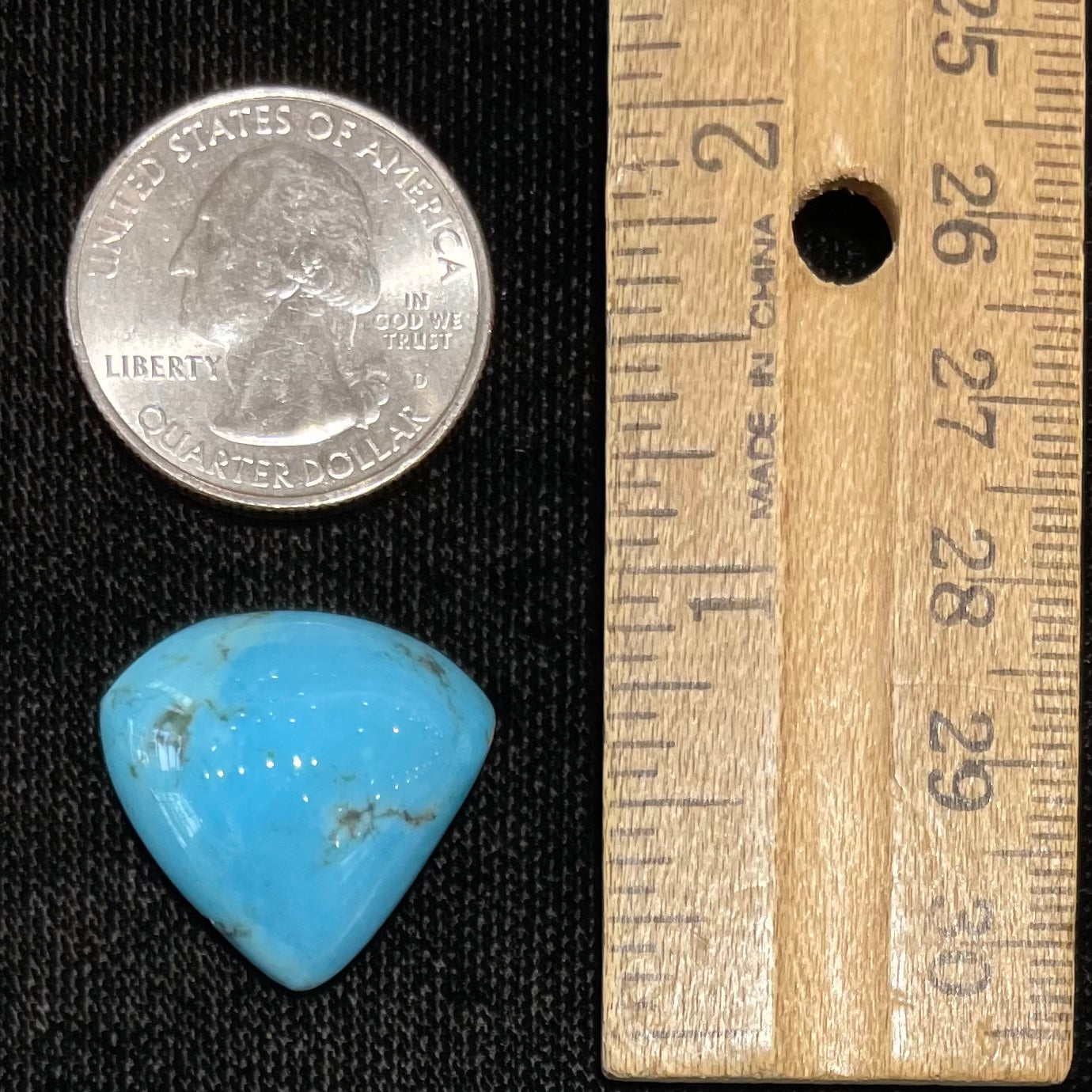 A loose, triangular cabochon cut blue turquoise stone from Sleeping Beauty Mine, Arizona.