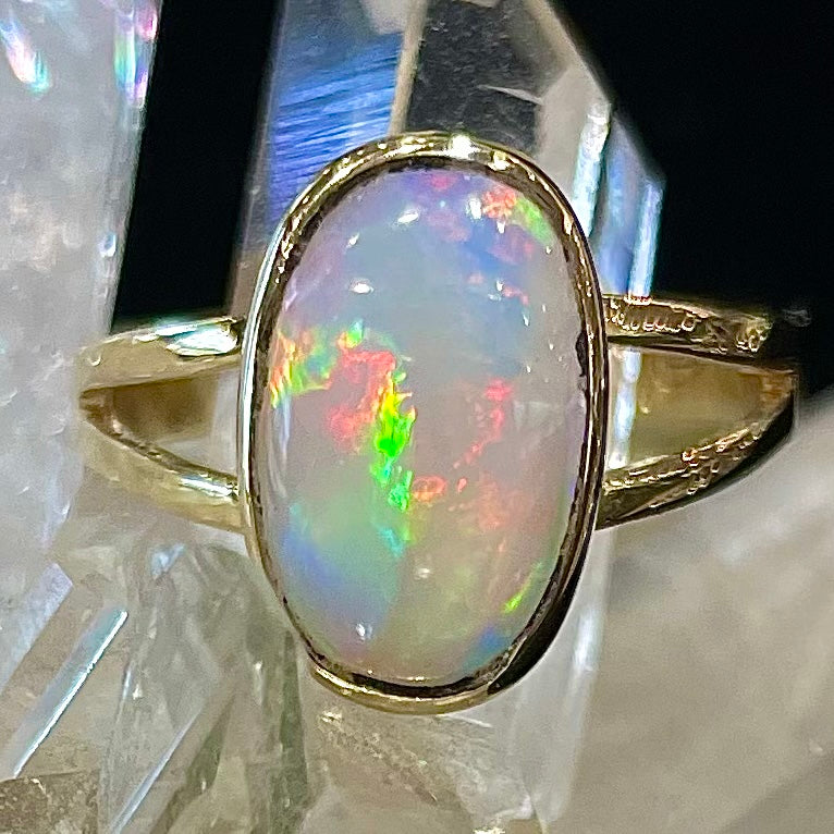 A handmade split shank white crystal opal solitaire ring in yellow gold.