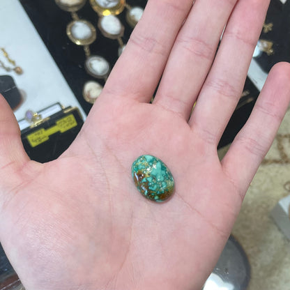 A loose, oval cabochon cut green and brown turquoise stone from Royston Mining District, Nevada.