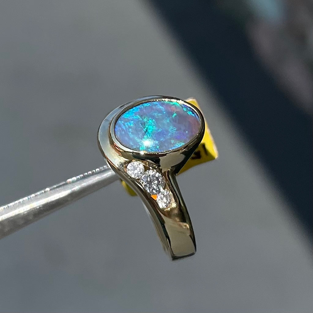 A yellow gold ring set with diamonds and a Lightning Ridge black opal from Australia.