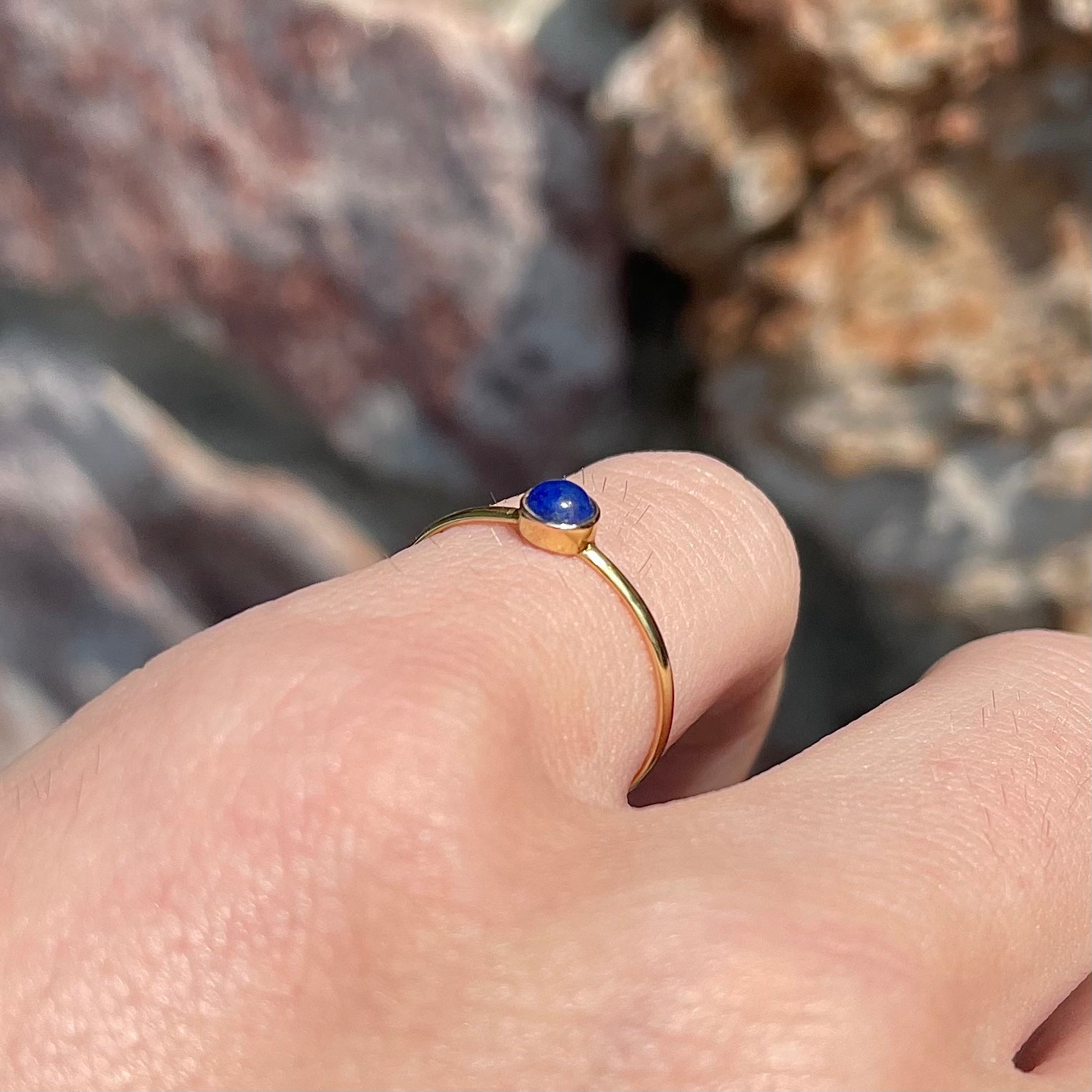 Round cabochon cut blue lapis lazuli stone set in a dainty simple yellow gold solitaire ring.