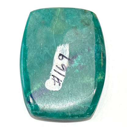 A polished, cushion shaped chrysocolla stone with azurite inclusions.